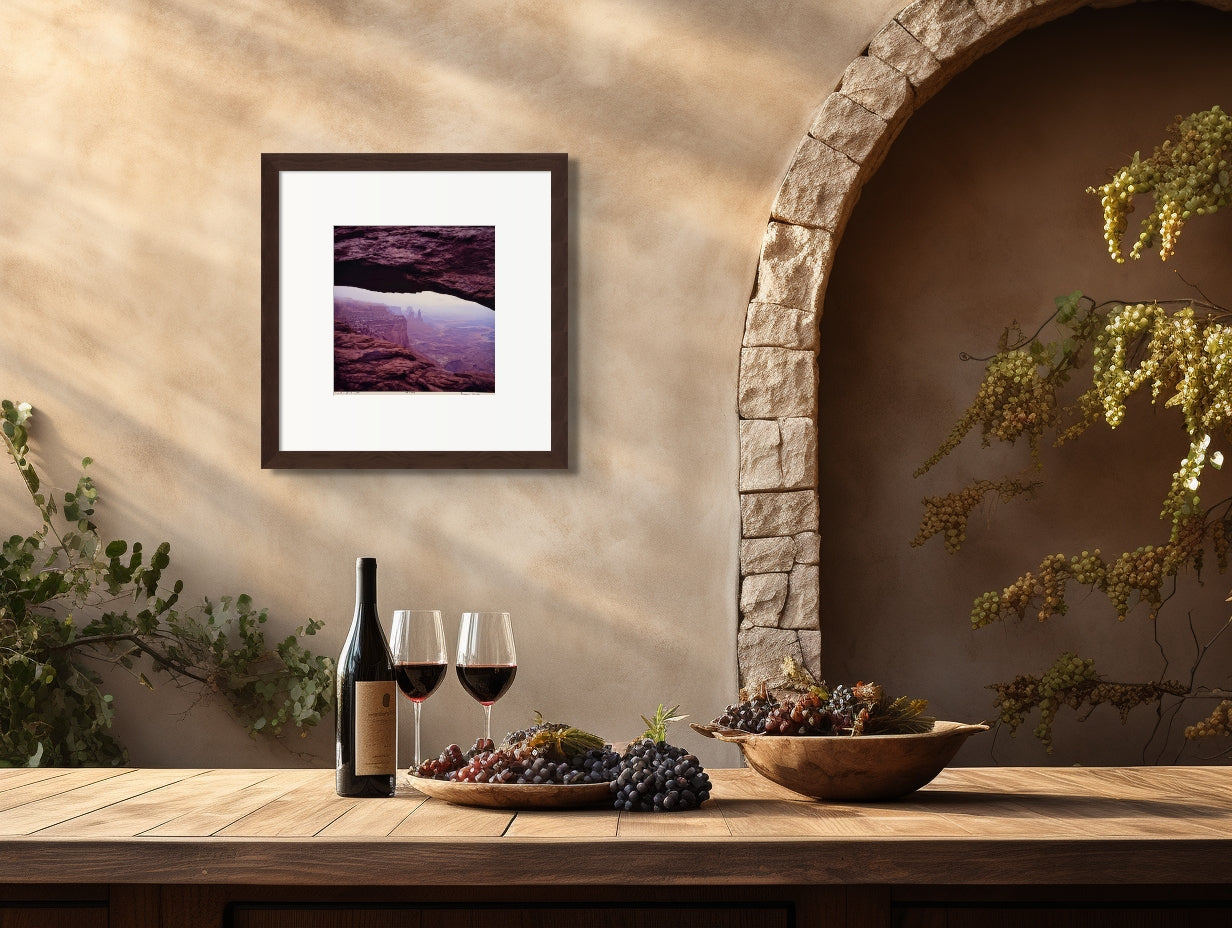 Photograph of Mesa Arch, UT. The photograph is 12 1/2 x 12 3/4 inches on a 16 x 20 inch archival matboard. The sun was rising when the capture was taken and the distant rock reflected the slight fog. The surrounding rocks are deep and brilliant in shades of subtle red terracotta and reddish brown. Unframed, but ready for the frames of your choice. Even the archival foam board in included so it is ready for you.